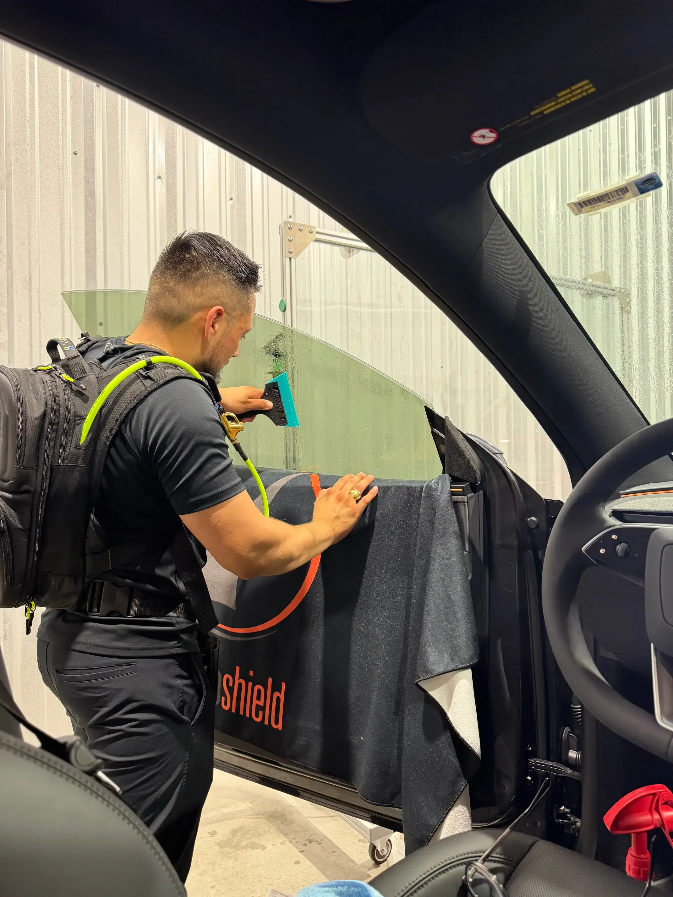 Technician applying window tinting to a car door window in College Station