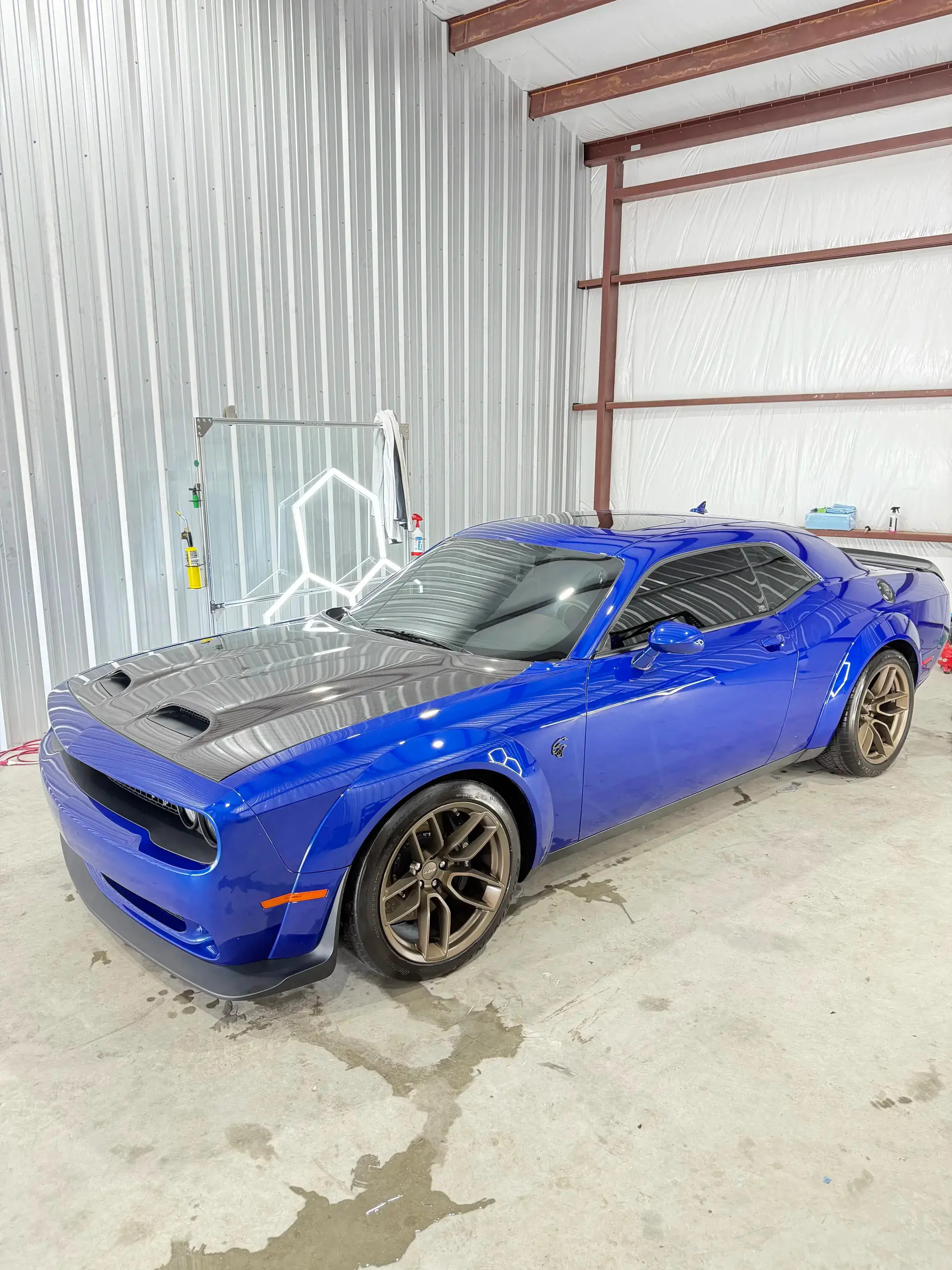 Blue Dodge Challenger parked in shop bay after windshield protection film installation in College Station