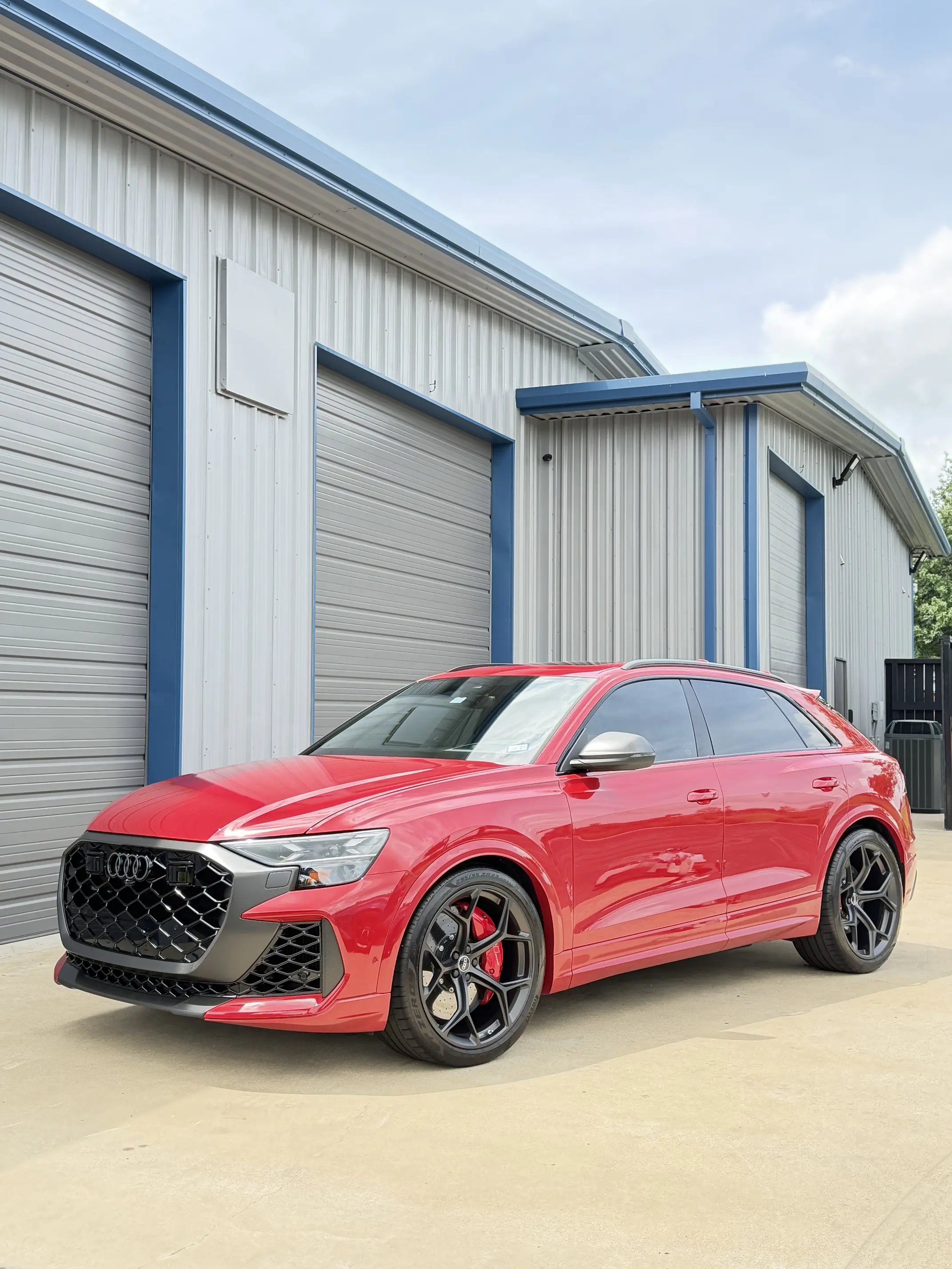 Red Audi wagon parked outside shop featuring professional window tinting Bryan TX