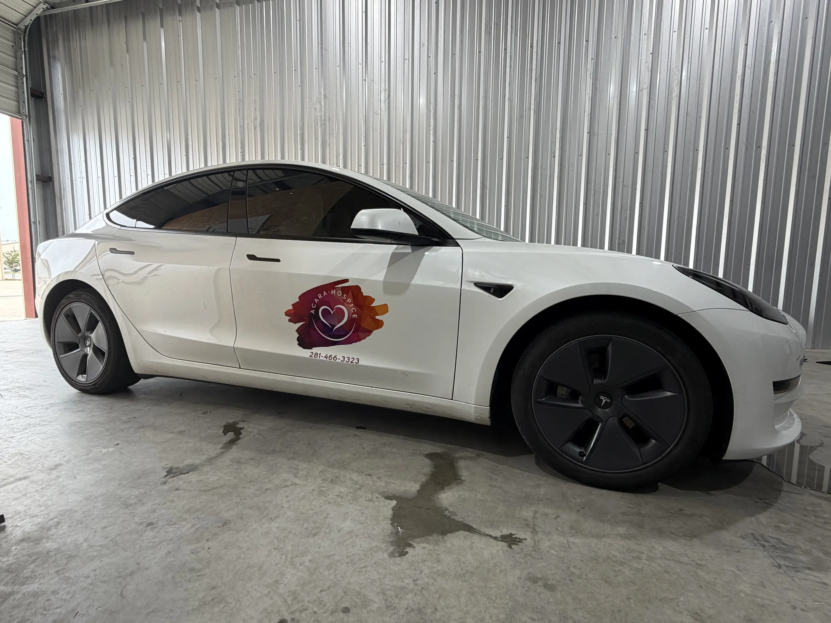 White Tesla inside shop featuring custom door graphics and vehicle wraps in College Station