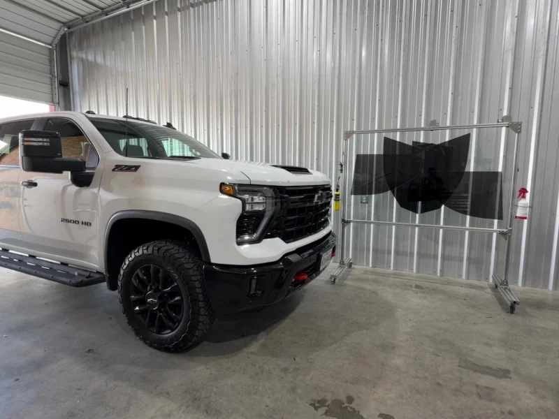 White GMC pickup truck inside shop after professional window tinting College Station area